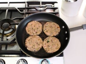 Overhead shot of four turkey burger patties in a frying pan.