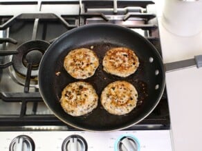 Overhead shot of four turkey burger patties in a frying pan.