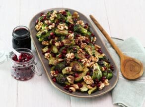 Horizontal shot of a platter filled with roasted brussels sprouts topped with pomegranate molasses.