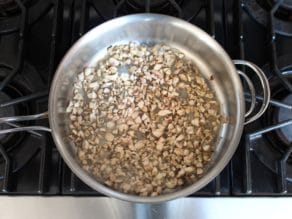 Chopped mushrooms in saute pan on stovetop.