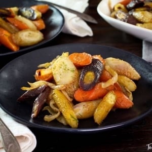 A plate of Spicy Roasted Carrots and Fennel, accompanied by a medley of vegetables including carrots and onions