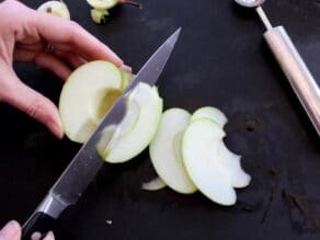 Hand slicing green apple.