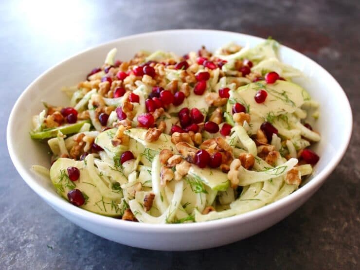 Close up of a bowl of Fennel Apple Salad with Cider Tahini Dressing, topped with pomegranate seeds.