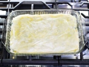 Overhead shot of uncooked spanakopita in a glass baking dish.