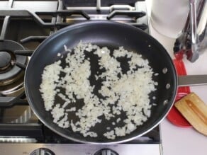 Horizontal overhead shot of onions sautéing in a frying pan.