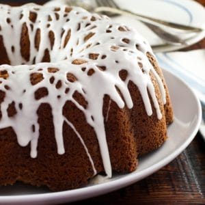 Close-up of a Sour Cream Coffee Cake topped with drizzled cream and served on a white plate