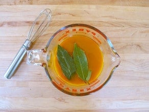 Chicken stock and seasonings in a glass measuring cup.