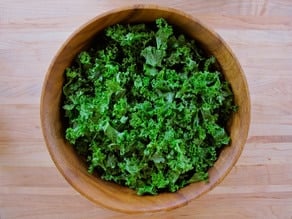 Washed and torn kale in a large salad bowl.