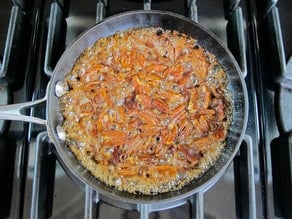 Maple syrup over pecans in a skillet.