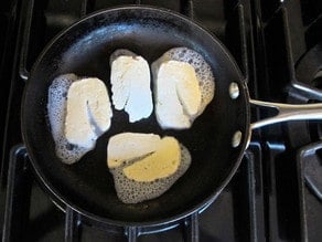 Halloumi cheese frying in a skillet.