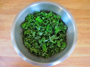 Massaging kale in a mixing bowl.