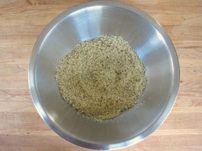 Panko breadcrumbs in stainless steel bowl tossed with olive oil and chili flakes.