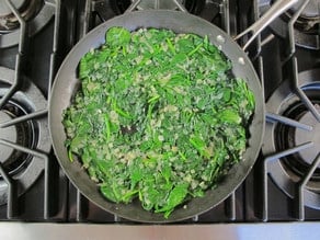 Fresh spinach wilting in a skillet.