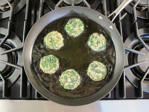 Keftes frying in a skillet.