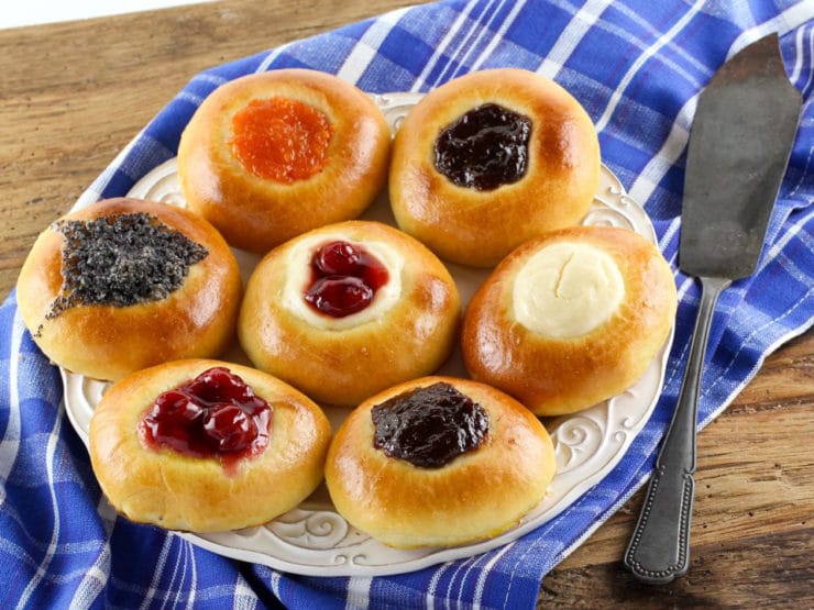 Kolache elegantly presented on a white plate, accompanied by a cake knife on the right side and set against a backdrop of a neatly folded tablecloth.