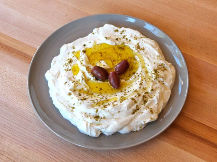 Strained yogurt labneh topped with olive oil and za'atar with three kalamata olives.