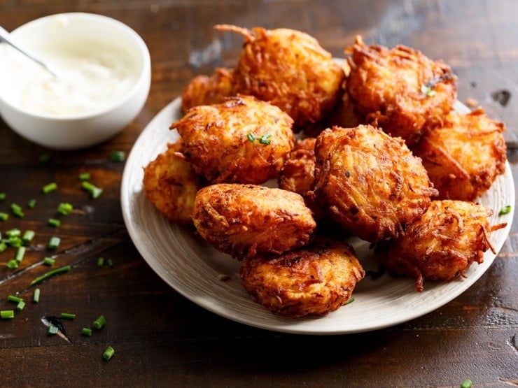 Latkes arranged on a white plate, accompanied by a dollop of sour cream.