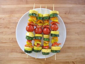 Putting sliced vegetables on skewers.