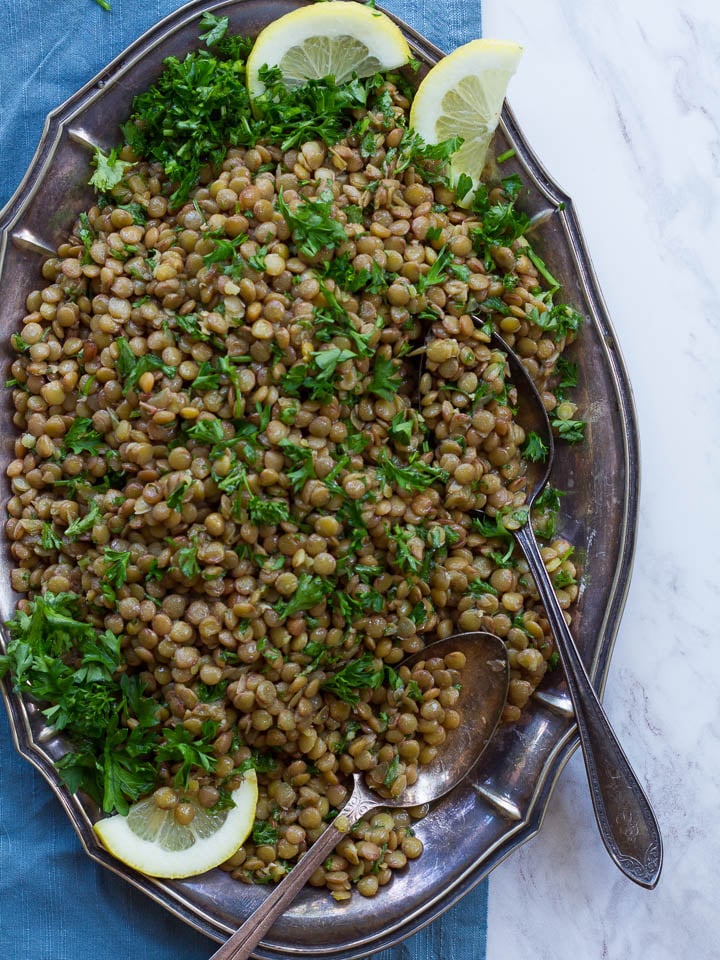 Vertical image of Lemon Lentil Parsley Salad on a long silver-like plate with spoons