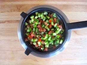 Straining chopped cucumbers and tomatoes.