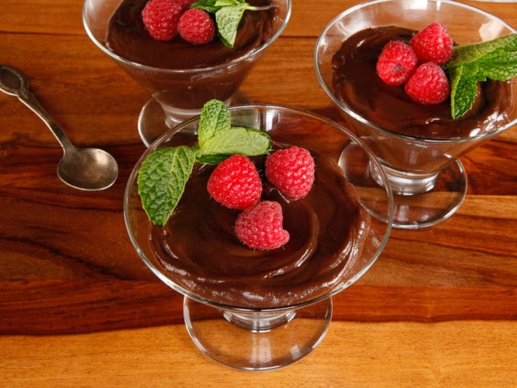 Horizontal image of vegan dark chocolate mousse served with raspberries and mint.