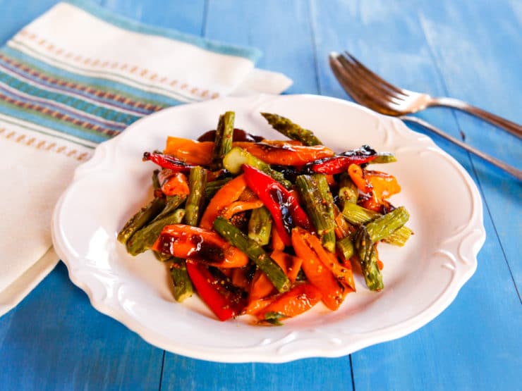 Roasted sweet mini peppers and asparagus on a plate with a fork