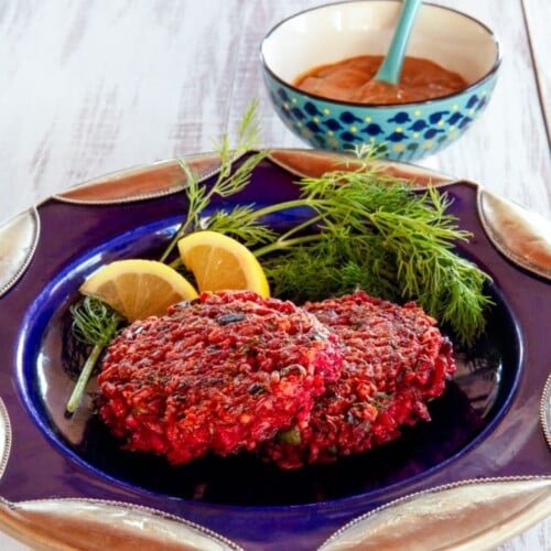 Close-up of The Red Rice and Beet Cake, a Crispy, fried vegetarian cake with a sweet Honey Mustard sauce served on a blue plate