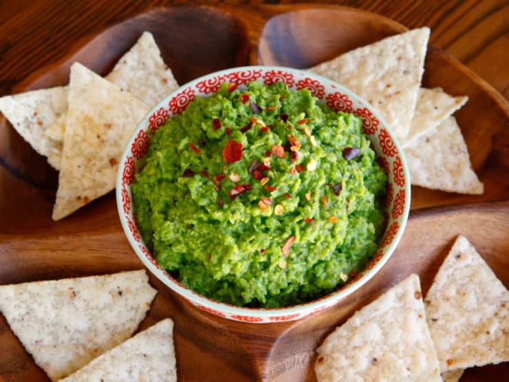 Overhead shot of Spring Pea Guacamole with nachos on sides