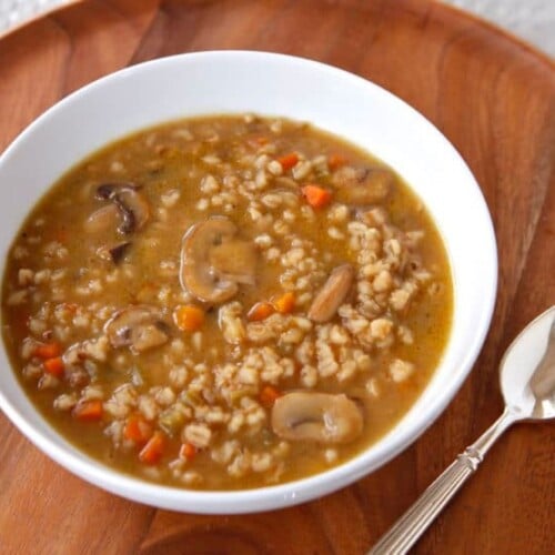 Image of a Mushroom Barley Soup served on a white bowl with spoon on side