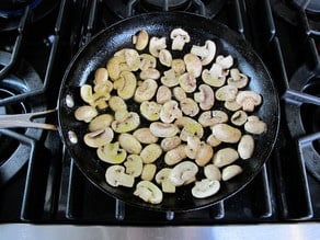 Sliced mushrooms browning in a skillet.