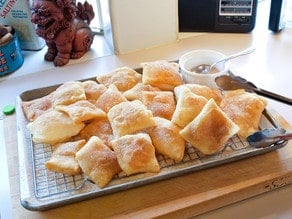 Sopapillas draining on a wire rack.