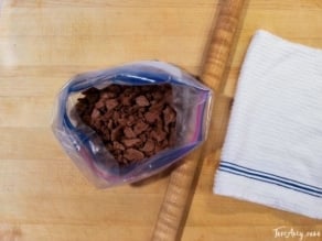 Crushed chocolate crackers inside a zip lock on a table with a towel on the side