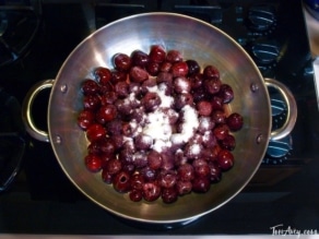 Cherries on a stainless steel container with sugar on top of stove