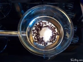 Chocolate chips on a bowl with milk and sugar on top of a stove