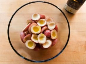 Overhead view of glass bowl filled with small red potatoes that have been cut in half with the center scooped out.