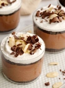 Horizontal shot of three glass dessert cups filled with a layered chocolate parfait.