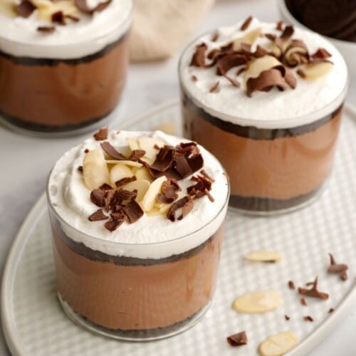 Horizontal shot of three glass dessert cups filled with a layered chocolate parfait.