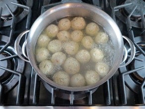 Matzo balls cooking in chicken stock.