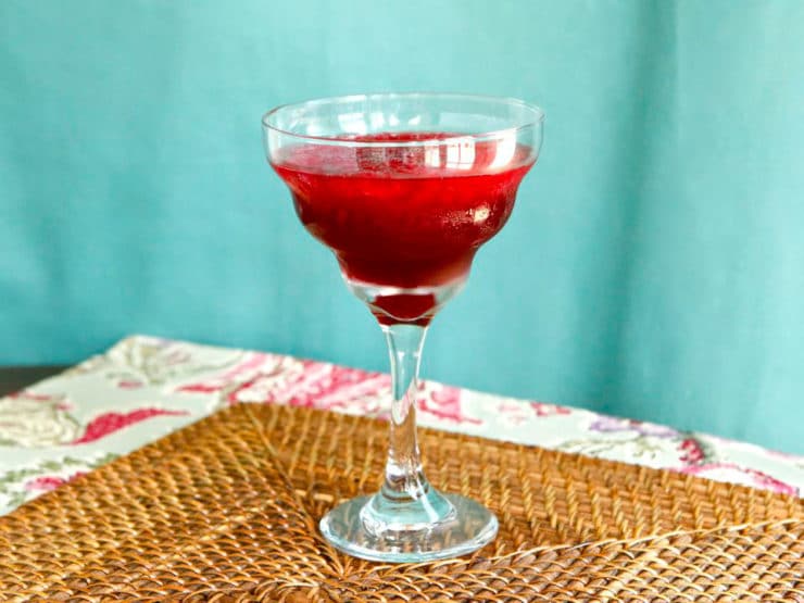 Persian Pomegranate Mocktail served on a fancy glass on top of a bamboo weaved table mat