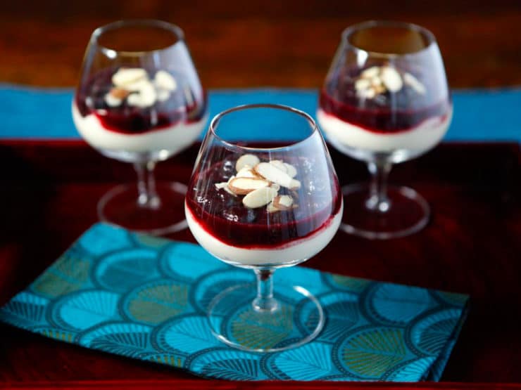 Three glasses of Cherry Cheesecake Shooters topped with almonds and berries, a delightful dessert