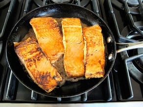 Searing salmon fillets in a skillet.