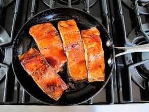 Searing salmon fillets in a skillet.