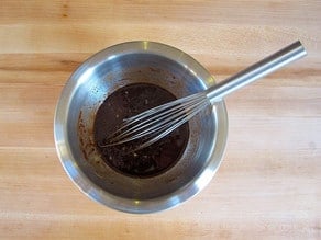 Whisking pomegranate molasses ingredients in a bowl.