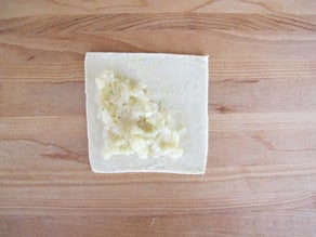 Mashed potato filling on puff pastry square.