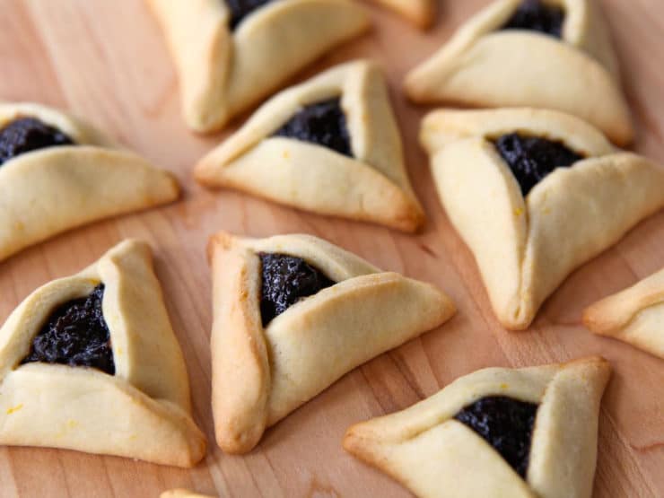 Prune-filled hamantaschen cookies on a wooden background.