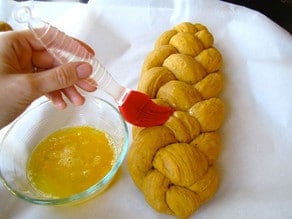 Brushing eggwash on braided challah.