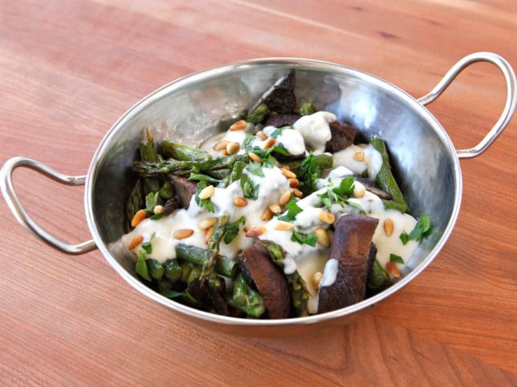 Roasted Portobellos & Asparagus with Goat Cheese Sauce serve on a stainless bowl on top of a wooden table