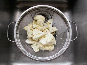 Rinsing cauliflower florets in a strainer.