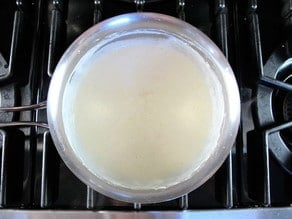 Milk added to a roux in a saucepan.