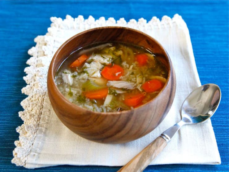 Horizontal shot of Rotisserie Chicken Rice Soup on a brown bowl and a spoon on top of a white cloth.